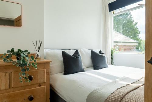 una camera da letto con un letto con cuscini blu e una finestra di Elmwood Cottage - Harrogate a Harrogate