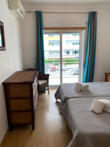 1 Schlafzimmer mit 2 Betten, einem Schreibtisch und einem Fenster in der Unterkunft Riviera Flat in Portimão