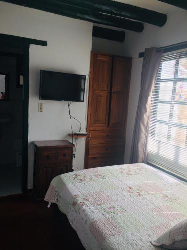 a bedroom with a bed and a flat screen tv at Casa Familiar Central Villa Diana in Villa de Leyva