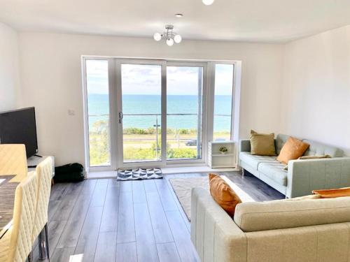a living room with a couch and a large window at Lovely New 2 Bedroom Condo with Stunning Seaviews in Penmaen-mawr