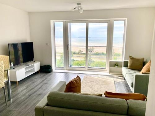 a living room with a couch and a television at Lovely New 2 Bedroom Condo with Stunning Seaviews in Penmaen-mawr
