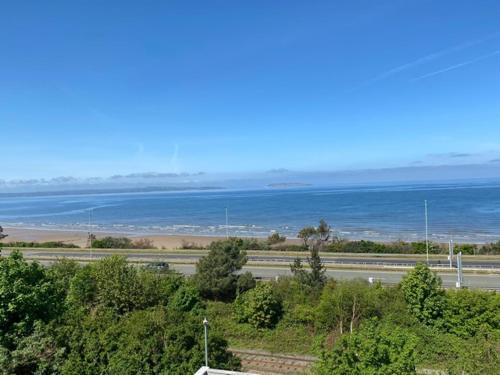 a view of the ocean and a road with trees at Lovely New 2 Bedroom Condo with Stunning Seaviews in Penmaen-mawr