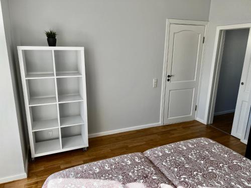 a bedroom with a bed and a white book shelf at Vilniaus 96 apartments in Ukmergė