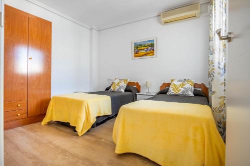 2 camas en una habitación con sábanas amarillas en Apartamento Isbilya, en Sevilla