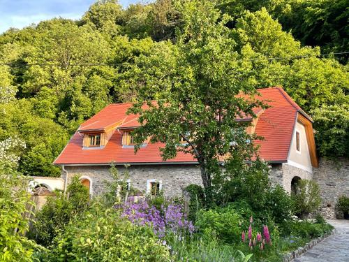 uma casa com um telhado vermelho e um jardim em Appartements Adam-Mühle em Spitz