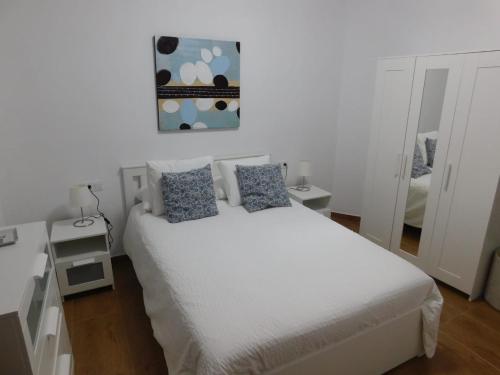 una camera da letto con un letto bianco con cuscini blu di Estudio SERMAR a Punta de Mujeres