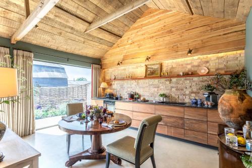 a kitchen with a wooden ceiling and a table and chairs at Cambridge Country Cottages in Cambridge