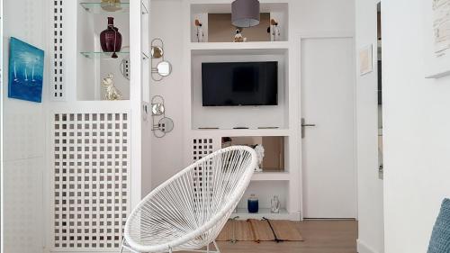 a white chair in a living room with a tv at Superbe appartement style architecte/unique** in Nice