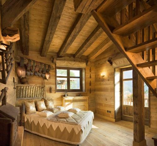 a bedroom with a bed in a room with wooden walls at Chalet Euthalia Restaurant & Suites in San Giacomo