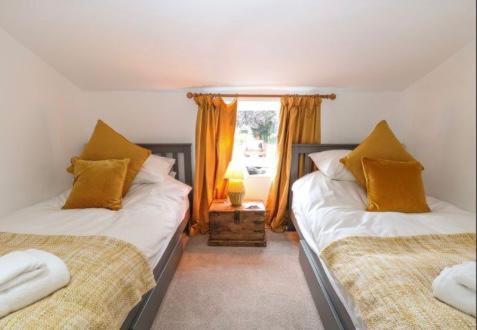 a bedroom with two beds and a window at Lavender Cottage in Mattishall