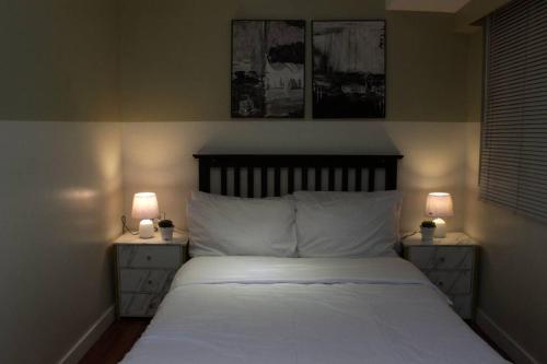a bedroom with a bed with two night stands with lamps at A2J BGC Luxury 2BR Loft Near Burgos Circle & Malls in Manila