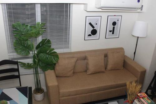 a living room with a brown couch and a plant at A2J BGC Luxury 2BR Loft Near Burgos Circle & Malls in Manila