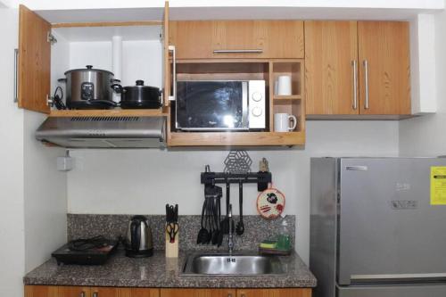 a kitchen with a sink and a microwave and a refrigerator at A2J BGC Luxury 2BR Loft Near Burgos Circle & Malls in Manila
