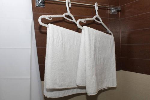 two white towels hanging on a towel rack in a bathroom at A2J BGC Luxury 2BR Loft Near Burgos Circle & Malls in Manila
