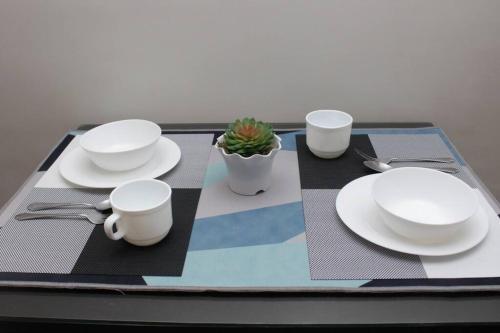 a table with white plates and a plant on it at A2J BGC Luxury 2BR Loft Near Burgos Circle & Malls in Manila