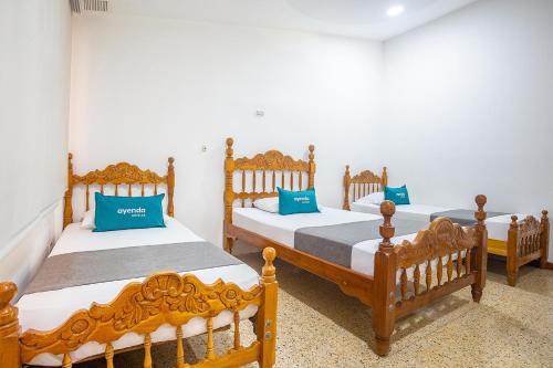 three beds in a room with blue pillows on them at Ayenda William Sanchez in Apartadó
