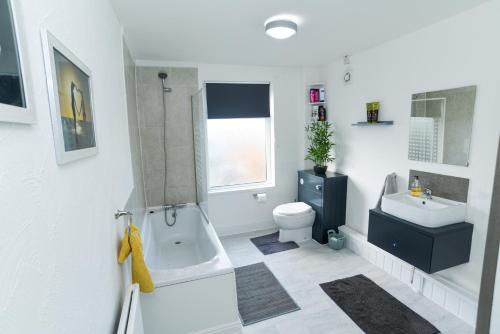 a bathroom with a tub and a toilet and a sink at Minshull House in Crewe