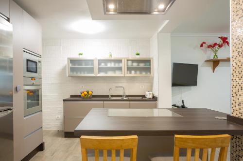 a kitchen with a sink and a counter with chairs at Casa Avenida del Agujero in Gáldar