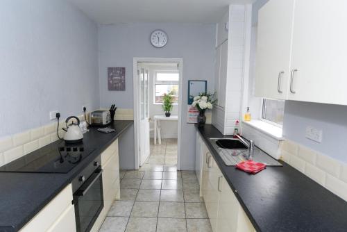 a kitchen with white cabinets and black counter tops at Minshull House in Crewe