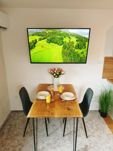 a wooden table with chairs and a tv on the wall at Apartmán u Ovečků - Nová Paka in Nová Paka