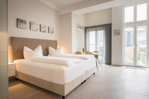two beds in a white bedroom with a window at Stylische Cityapartments Benedikt in Klagenfurt
