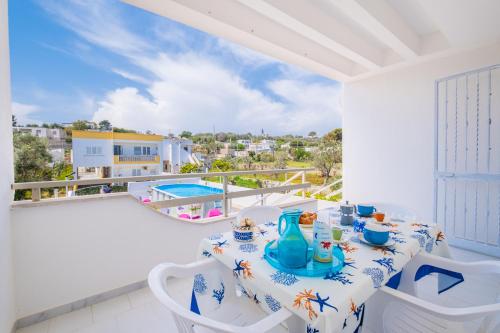 een tafel en stoelen op een balkon met uitzicht op een zwembad bij Chiara & Giulia Apartments by HDSalento in Leuca