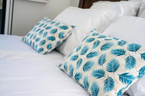 Una cama con almohadas azules y blancas. en Le Clos des Fantaisies en Rivedoux-Plage