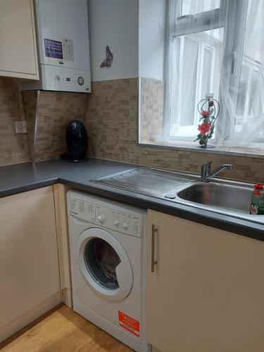 uma cozinha com uma máquina de lavar roupa e um lavatório em Lux Apartment in Gatwick em Crawley