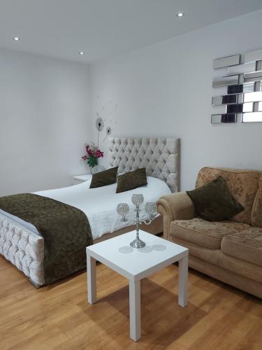 a bedroom with a bed and a couch and a table at Lux Apartment in Gatwick in Crawley