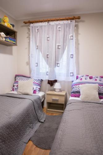 a bedroom with two beds and a window at FÜGE-FA-HÁZ VÁSÁROSNAMÉNY - GERGELYIUGORNYA in Vásárosnamény