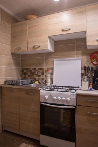 a kitchen with a white stove and wooden cabinets at FÜGE-FA-HÁZ VÁSÁROSNAMÉNY - GERGELYIUGORNYA in Vásárosnamény