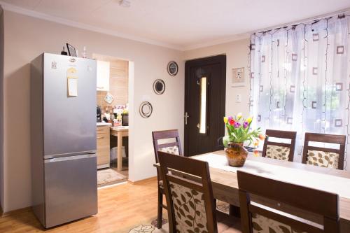 a kitchen and dining room with a table and a refrigerator at FÜGE-FA-HÁZ VÁSÁROSNAMÉNY - GERGELYIUGORNYA in Vásárosnamény