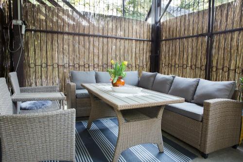 a patio with a table and wicker chairs at FÜGE-FA-HÁZ VÁSÁROSNAMÉNY - GERGELYIUGORNYA in Vásárosnamény