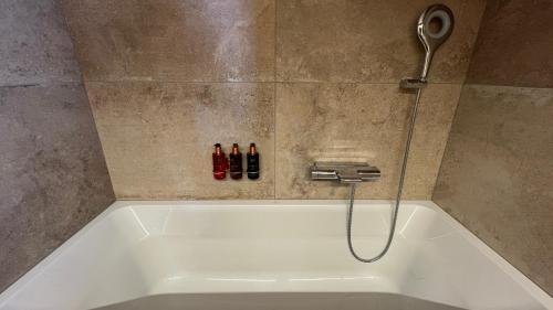a bath tub with a shower head and three bottles at Zenith Views by Villars Luxury in Villars-sur-Ollon