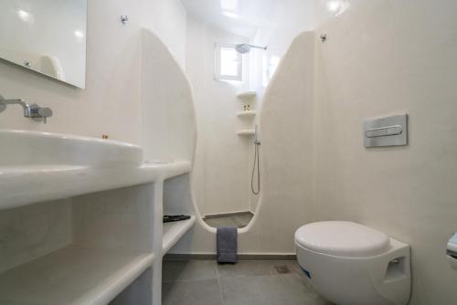 a white bathroom with a toilet and a sink at The Muses of Santorini Private Jacuzzi Suites in Vóthon