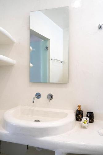 a white bathroom with a sink and a mirror at The Muses of Santorini Private Jacuzzi Suites in Vóthon