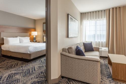 a hotel room with a bed and a chair at Candlewood Suites Ofallon, Il - St. Louis Area by IHG in O'Fallon