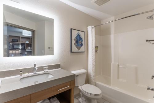 a bathroom with a sink and a toilet and a mirror at Candlewood Suites Ofallon, Il - St. Louis Area by IHG in O'Fallon