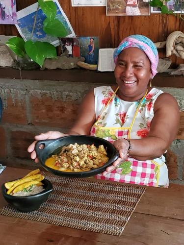 a woman holding a pan of food on a table at Posada El Esfuerzo in Nuquí