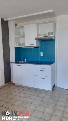 une cuisine avec des placards blancs et un mur en carrelage bleu dans l'établissement L HACIENDA - appartement 4 à 5 personnes proche plage et port - Parking, à Saint-Cyprien