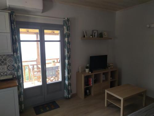a living room with a door and a television and a table at Eden View in Sotír