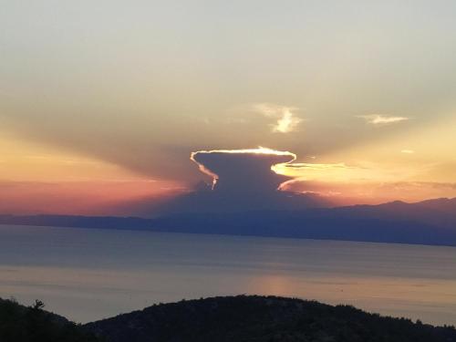 a cloud in the sky over the water at sunset at Eden View in Sotír