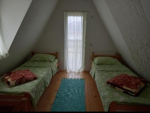um quarto no sótão com 2 camas e uma janela em Vila Suza em Jezdići