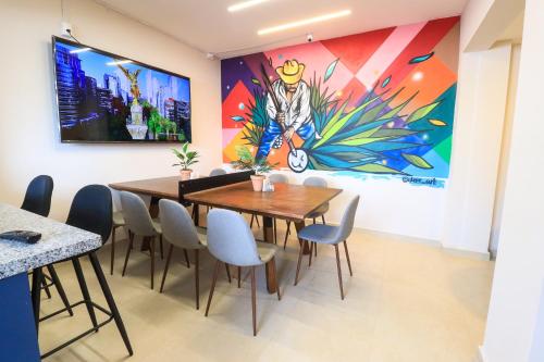 a dining room with a large painting on the wall at Colmena Hotel CDMX Suites Roma in Mexico City