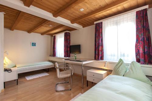 a bedroom with a bed and a desk and a window at Seminarhotel Linde Stettlen in Bern