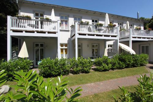 ein großes weißes Haus mit Balkonen und Büschen in der Unterkunft "Haus Rubert" 4 Sterne Fewos, strandnah in Zinnowitz
