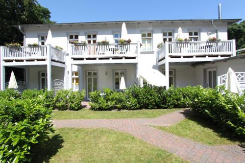 ein großes weißes Haus mit Balkon und Gehweg in der Unterkunft "Haus Rubert" 4 Sterne Fewos, strandnah in Zinnowitz
