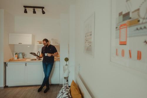 a man standing in a kitchen looking at his watch at Studio apartman Centar in Ðakovo