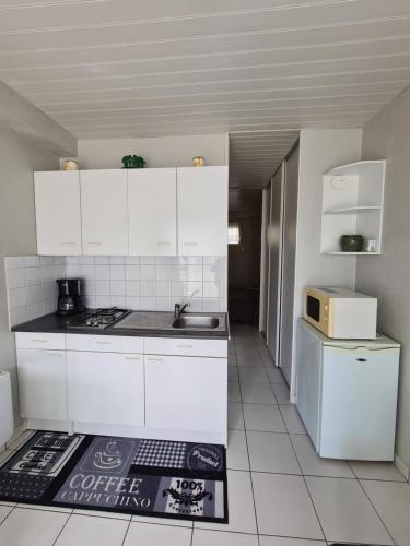 a white kitchen with a sink and a refrigerator at 2 logements séparés 2 et 5 couchages au Rez-de-Chaussée à Chambretaud, 5 min Puy du Fou in Chambretaud