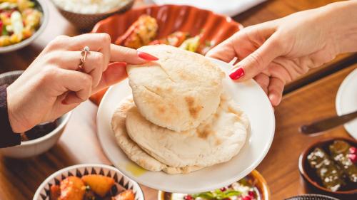 two hands holding a plate of food on a table at InterContinental Budapest by IHG in Budapest